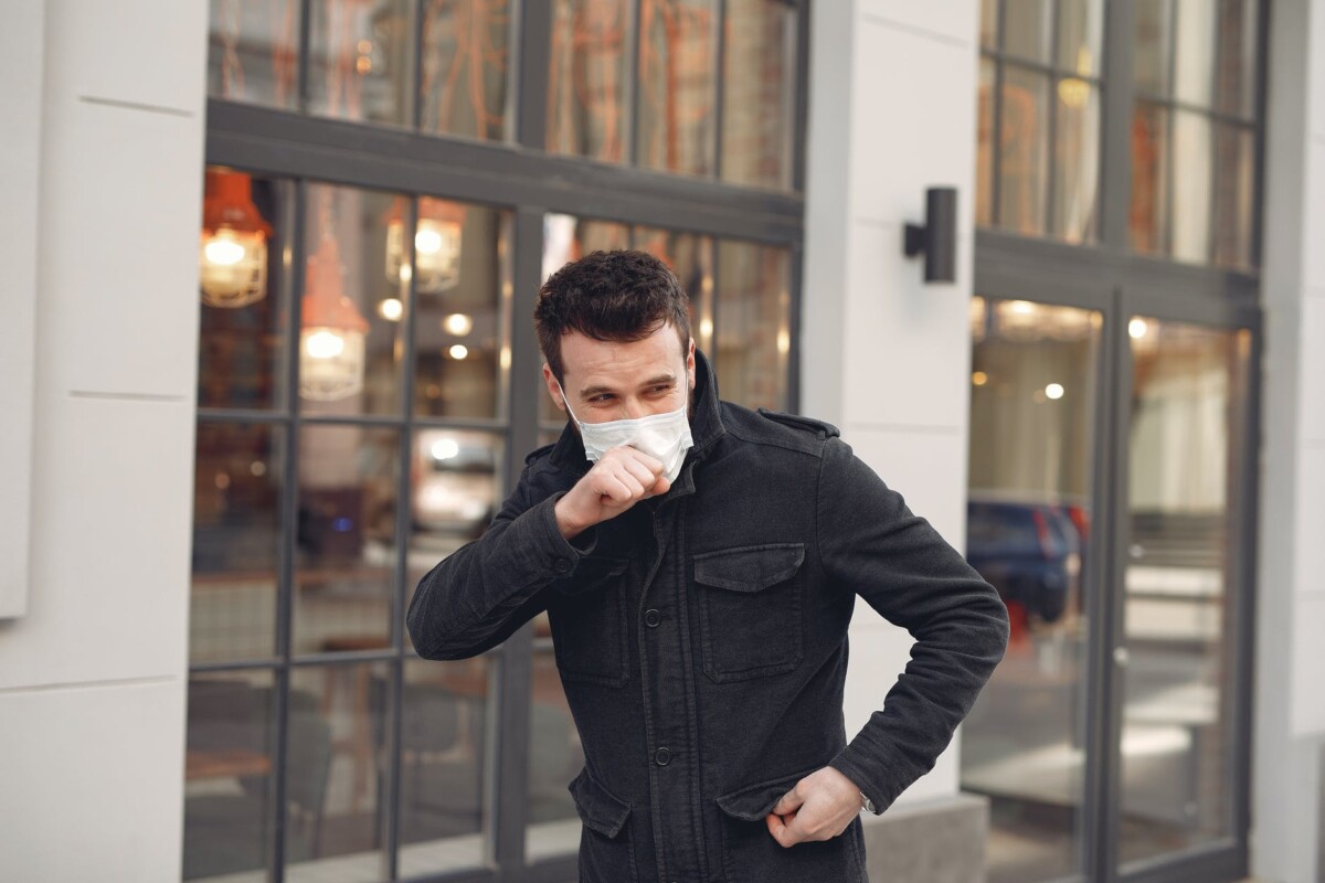 sick young man in medical mask walking on street during coronavirus pandemic
